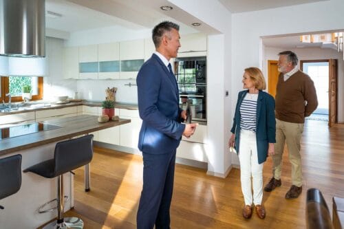 real estate agent shows luxury home to buyers